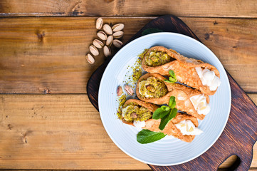 Cannoli Sicily. Traditional Italian sweet with ricotta and various fillings. Food on a wooden cutting board.