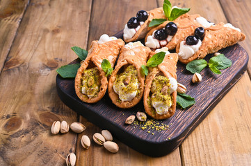 Cannoli Sicily. Traditional Italian sweet with ricotta and various fillings. Food on a wooden cutting board