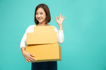 Happy Asian woman holding package parcel box and and showing ok, Delivery courier and shipping service concept