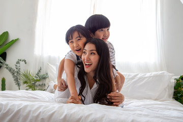 Obraz na płótnie Canvas Happiness of Asian family with mom and son and daughter hug mother on white bed in bedroom, Feeling happy and family relationship concept