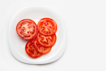 Sliced tomato on a white plate. White isolated background. Copy space.