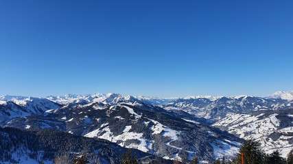 Zimowy widok na trasy narciarskie oraz panoramę Alp w słoneczny mroźny dzień w Wagrain w Austrii.