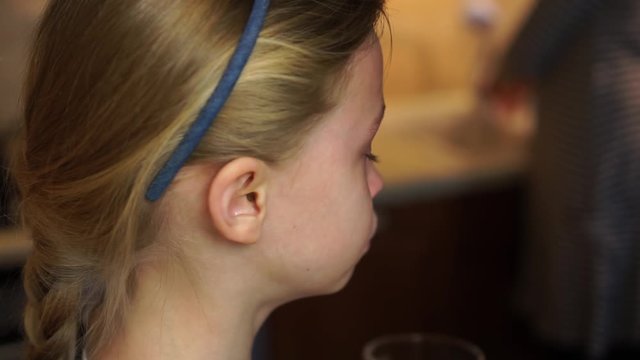 Blond child girl crying tears down her face offended by parents in home kitchen. Child abuse bad childhood