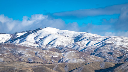 Light snow partially covers the foothills of Boise, Idaho on a clear winter day.