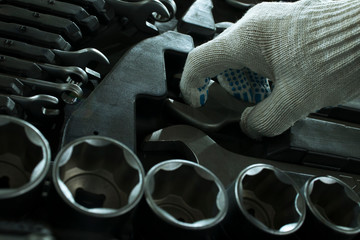 Obraz premium Hand of a man in a glove takes a wrench from a toolbox