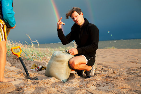 young father with son on beach digging pit under the rainbow, playing, looking for treasure, lifestyle happy family on vacation