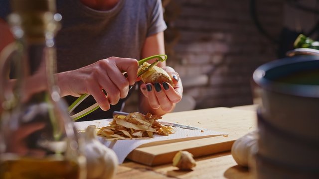 Woman peeling ginger for cooking in kitchen