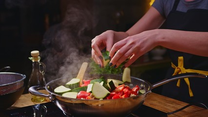 Woman cooking frying in kitchen in wok pan
