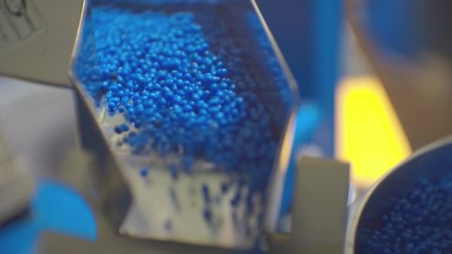 movement of blue plastic granules in production equipment.closeup.