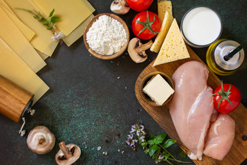 Food background italian. Ingredients for cooking lasagna with chicken and mushrooms on a dark stone background. Top view flat lay background. Copy space.