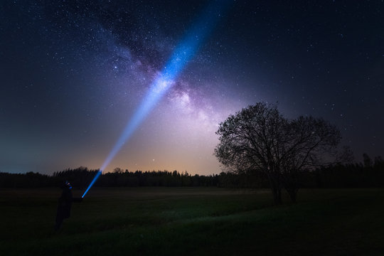 Low angle view of person illuminating the night sky and the milky way/galactic core with flashlight - Powered by Adobe