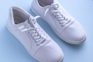 White sneakers on light blue colour background, flat lay top view minimal background. 
