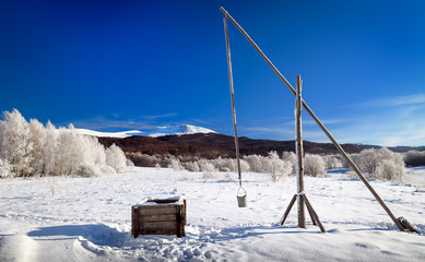 Frosty winter morning in the mountains (Bieszczady National Park). View of the well - crane in Wolosate village. In the background: Tarnica - the highest peak of the Bieszczady Mountains in Poland.  © Zbigniew