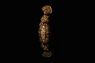A bronze figure of a girl in a traditional Russian dress and kokoshnik stands on a glossy black glass, in which her reflection is visible