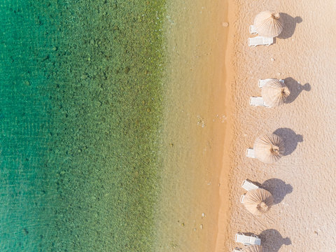 Aerial view of white umbrellas at Vela luka beach during the summer in Baska, Krk island, Croatia.