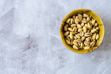 Brown bowl with shell pistachios on a gray background. Healthy eating concept.