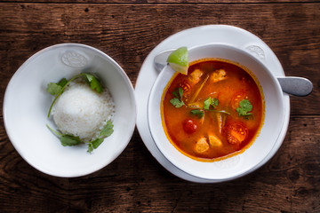 A bowl of soup tom yam on a plate