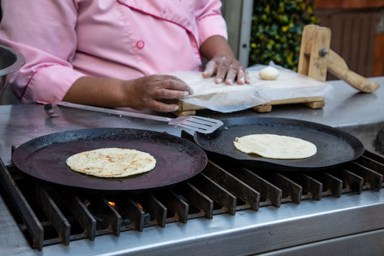 Closeup Of Woman Hands Making Tortillas On Comal.