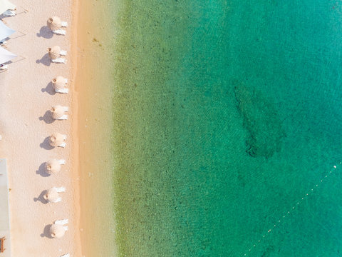 Aerial view of white umbrellas at Vela luka beach during the summer in Baska, Krk island, Croatia.