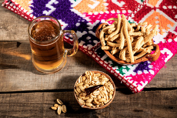 Beer jar with delicious Mexican snacks on rustic wooden table.