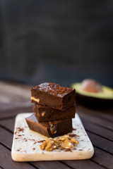 Cremoso brownie con nueces y cacao en polvo. Fondo rústico y oscuro.