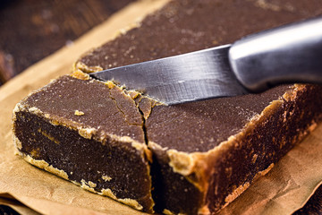 sweet rapadura, being cut by knife, macro photo. Candy made from sugar cane