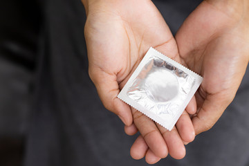Woman hand holding and condom sitting on sofa background,protection, safe sex,contraceptive means.