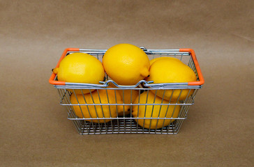 Ripe yellow lemons in the shopping basket on the brown background. Healthy life style concept. Delivery concept. 