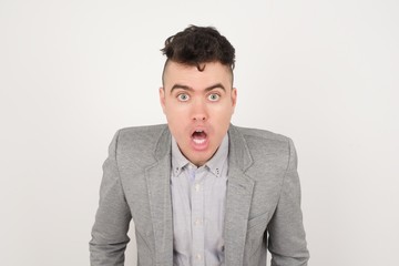 Attractive young man having stunned and shocked look, with mouth open and jaw dropped, listening to friend's story in full disbelief, exclaiming: Wow, I can't believe this. Surprised boy. Shock