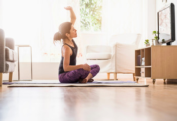 Side-view of woman exercising in living room
