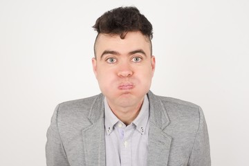 Handsome young man puffing cheeks with funny face. Mouth inflated with air, crazy expression.