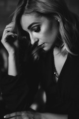 Fototapeta premium Beautiful elegant woman blonde in a black dress with feathers in retro style 1920 fashion. Soft selective focus. Black and white art photo.