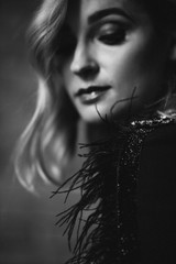 Beautiful elegant woman blonde in a black dress with feathers in retro style 1920 fashion. Soft selective focus. Black and white art photo.