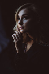 Beautiful elegant woman blonde in a black dress with feathers in retro style 1920 fashion. Soft selective focus.