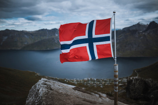 Norway, Senja, Norwegian flag with fjord and mountains in background