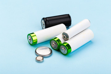 many new and used batteries of different shapes, AA, round batteries on a blue background.