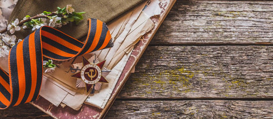 May 9, Victory Day holiday. Holiday card with order, St. George ribbon, flowers and military cap. May 9 background, copy space and translation with Victory Day.