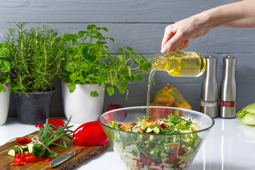 salad from fresh vegetables in a plate on a table. bowl of salad with vegetables and greens on white table. Women preparing vegetable salad- close up shot. Domestic kitchen. Vegetarian food. spices in