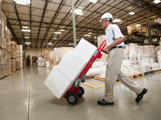 Man pushing hand truck in warehouse