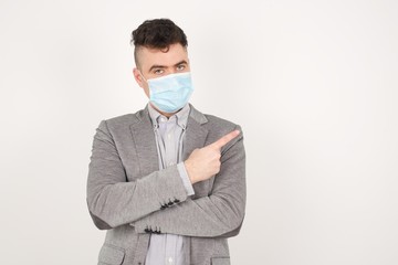 Excited surprised fashionable boy points happily aside on copy space of gray background for your fashion clothing advertising information or promotional text.