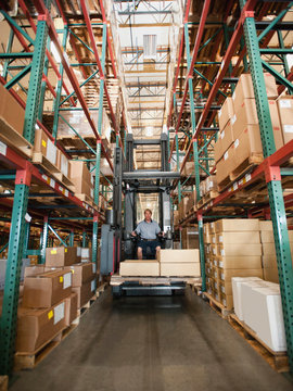 Forklift truck stacking boxes in warehouse
