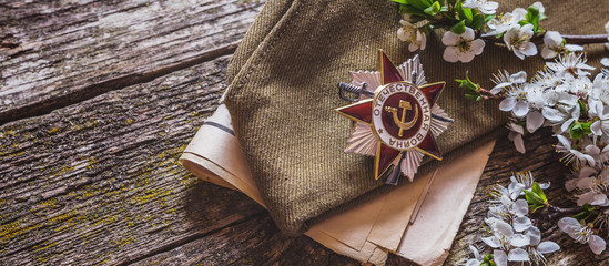 May 9, Victory Day holiday. Holiday card with order, St. George ribbon, flowers and military cap. May 9 background, copy space and translation with Victory Day.