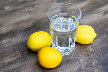 Glass of water with lemons on a wooden table.