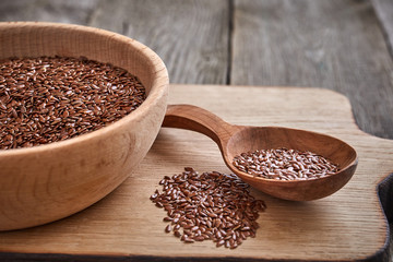 Flax seeds and a wooden spoon on a wooden table. Wooden bowl on Cutting board. Healthy food concept.