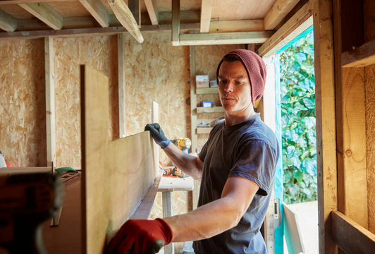 Carpenter working in shed with a sheet of plywood