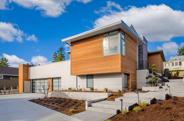 Fototapeta na wymiar Beautiful modern home exterior on bright sunny day with blue sky and clouds. House features elegant design and three car garage