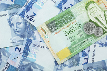 A macro image of a one dinar bank note from Jordan on a bed of Brazilian two reais bank notes close up