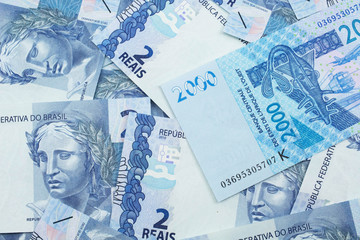 A close up image of a blue, two thousand, West African franc bank note in macro on a background of Brazilian two real bills