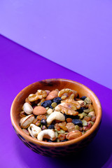 Mixed nuts in a bowls on color background .