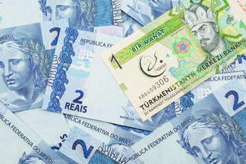 A one manat bank note from Turkmenistan close up in macro with an assortment of Brazilian two reais bank notes.